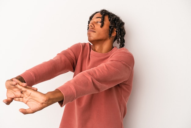 Photo jeune homme afro-américain isolé sur fond blanc étirant les bras, position détendue.