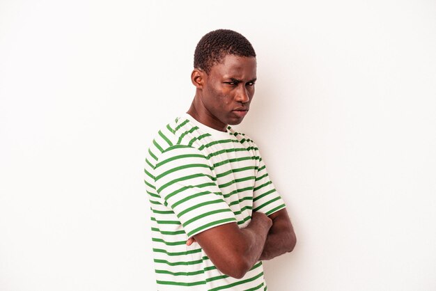 Jeune homme afro-américain isolé sur fond blanc fronçant le visage de mécontentement garde les bras croisés