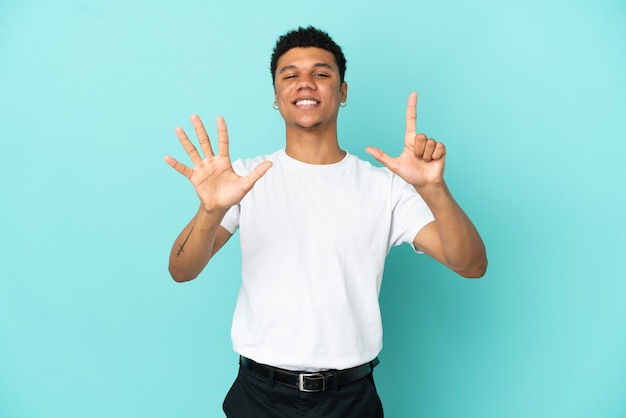 Jeune homme afro-américain isolé sur fond bleu comptant sept avec les doigts