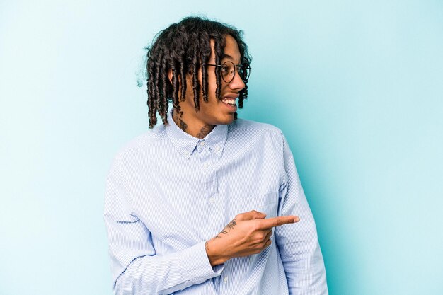 Jeune homme afro-américain isolé sur fond bleu regarde de côté souriant joyeux et agréable