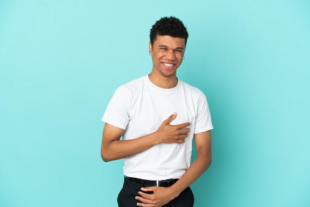 Jeune homme afro-américain isolé sur fond bleu souriant beaucoup