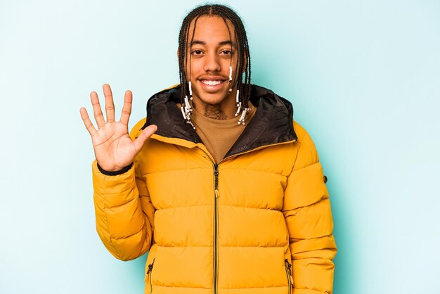 Jeune homme afro-américain isolé sur fond bleu souriant joyeux montrant le numéro cinq avec les doigts