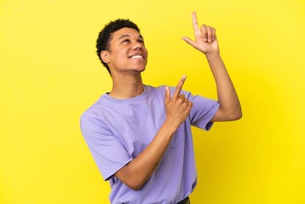 Jeune homme afro-américain isolé sur fond jaune pointant avec l'index une excellente idée