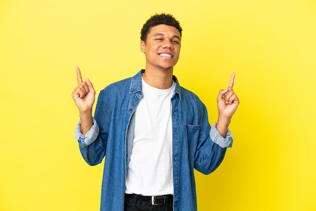 Jeune homme afro-américain isolé sur fond jaune pointant vers une excellente idée