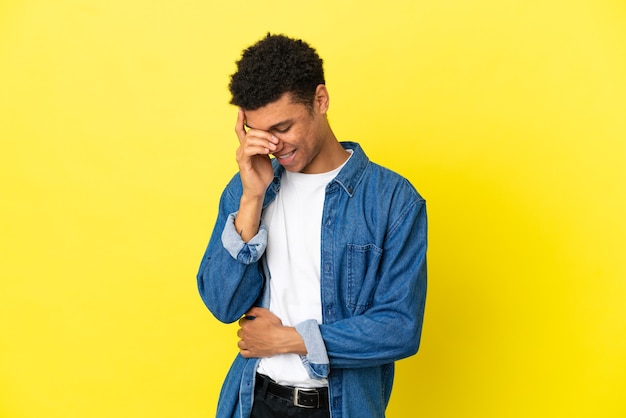 Jeune homme afro-américain isolé sur fond jaune en riant