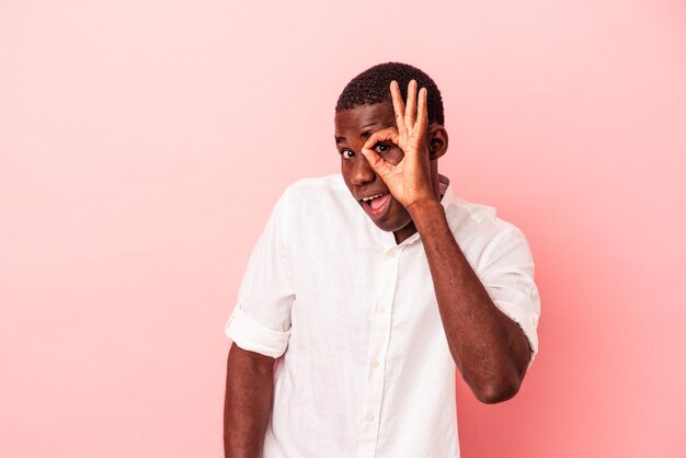 Jeune homme afro-américain isolé sur fond rose excité en gardant un geste correct sur les yeux.