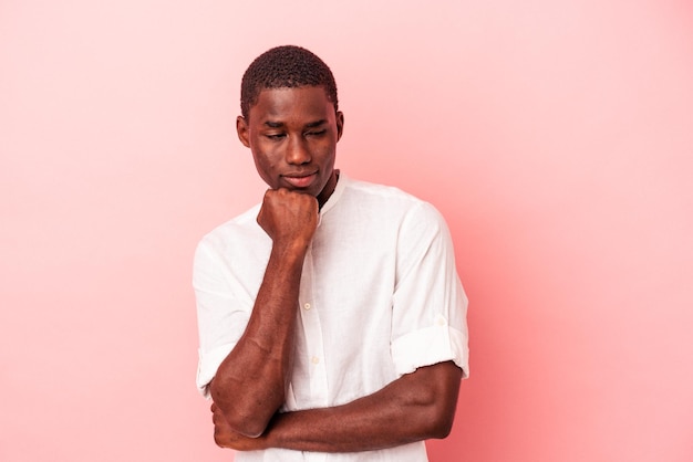 Jeune homme afro-américain isolé sur fond rose souriant heureux et confiant touchant le menton avec la main