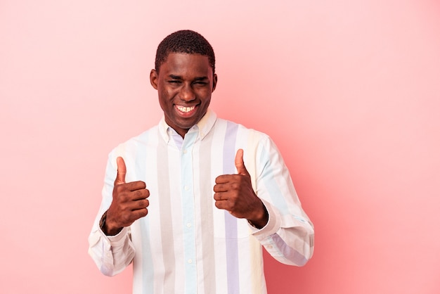 Jeune homme afro-américain isolé sur fond rose souriant et levant le pouce vers le haut