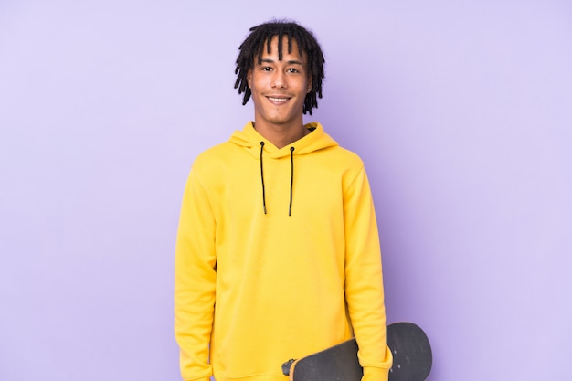 Jeune homme afro-américain isolé sur fond violet avec un patin