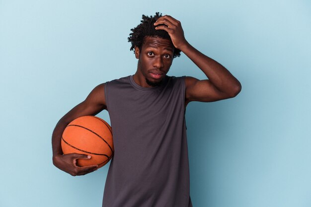 Jeune homme afro-américain jouant au basket-ball isolé sur fond bleu étant choqué, elle s'est souvenue d'une réunion importante.