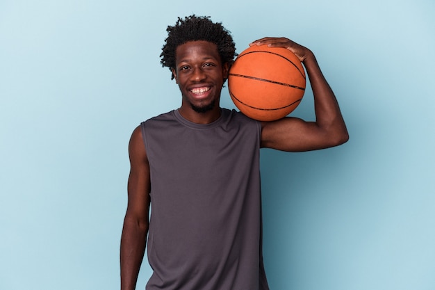 Jeune homme afro-américain jouant au basket-ball isolé sur fond bleu