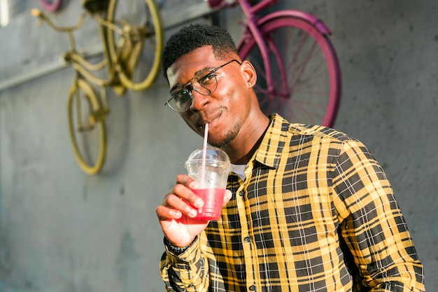 Jeune homme afro-américain joyeux sur la ville s'amusant et tenant un cocktail Homme en vacances d'été Concept de vacances de style de vie de loisirs et de boissons d'été