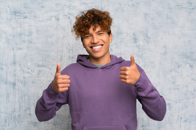 Jeune homme afro-américain sur le mur de grunge donnant un geste du pouce