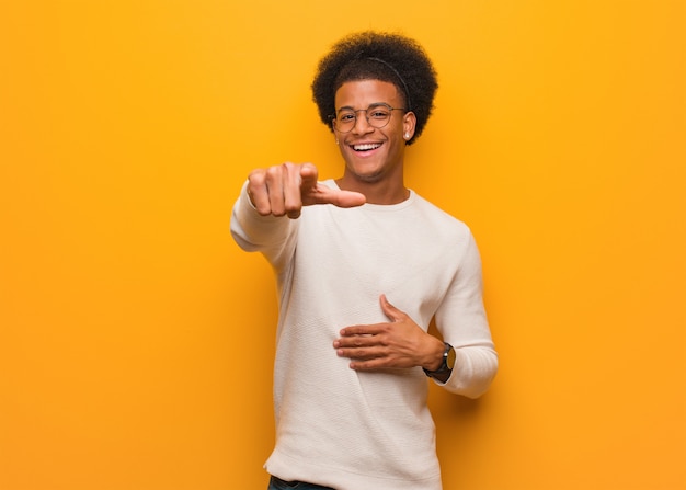 Jeune homme afro-américain sur un mur orange rêve d'atteindre ses buts et objectifs