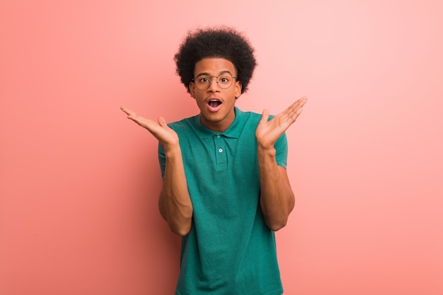 Photo jeune homme afro-américain sur un mur rose surpris et choqué