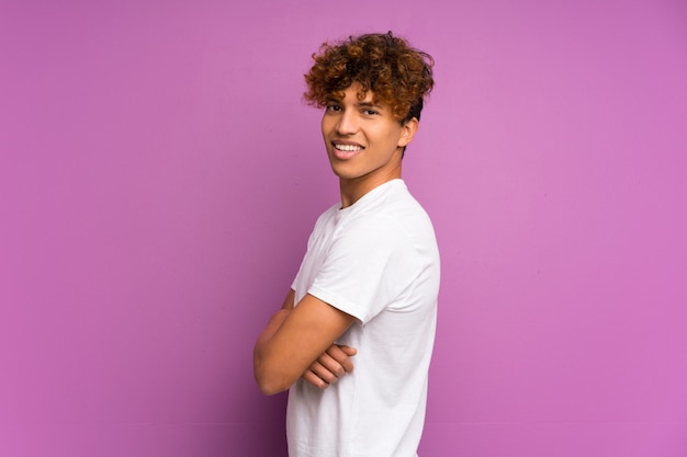 Jeune homme afro-américain sur un mur violet isolé avec les bras croisés et impatient