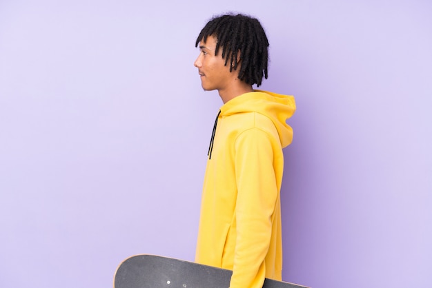 Photo jeune homme afro-américain sur mur violet avec un patin