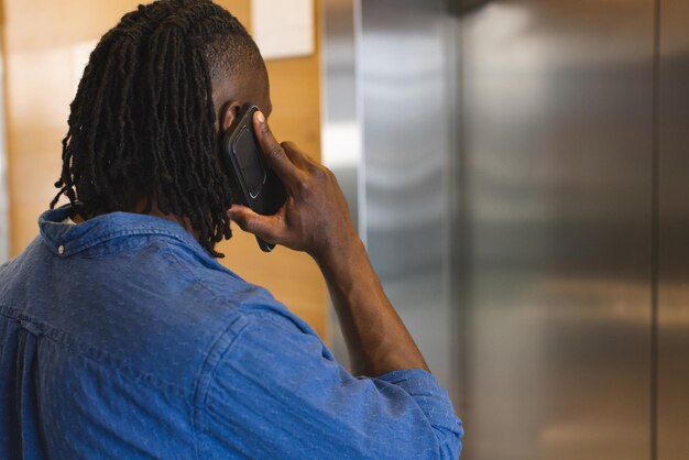 Photo un jeune homme afro-américain parle sur un smartphone dans un bureau d'affaires moderne