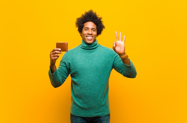 Jeune homme afro-américain avec un portefeuille contre l'orange