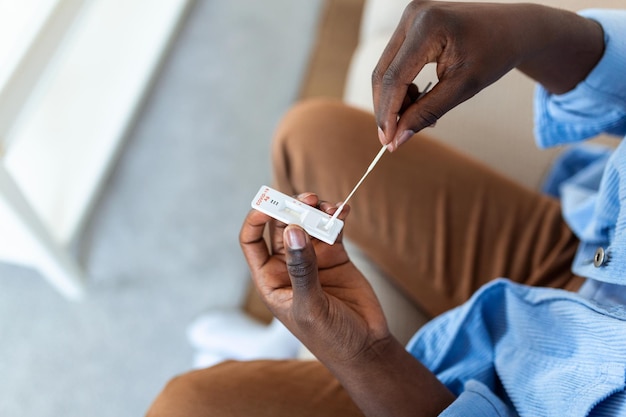 Jeune homme afro-américain prenant des tests à domicile d'auto-écouvillonnage pour COVID19 à la maison avec un kit d'antigène Présentation d'un bâton nasal pour vérifier l'infection de la pandémie de quarantaine de coronavirus