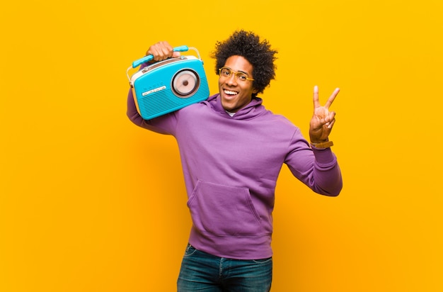 Jeune homme afro-américain avec une radio vintage contre orange b