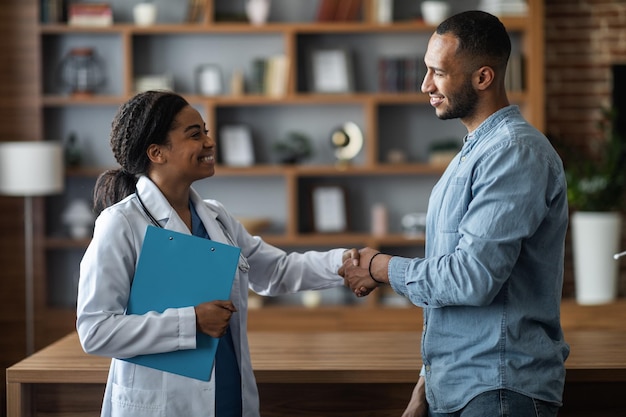 Jeune homme afro-américain reconnaissant serrant la main du médecin