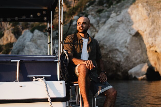 Jeune homme afro-américain se détendre sur un voilier en pleine mer au coucher du soleil