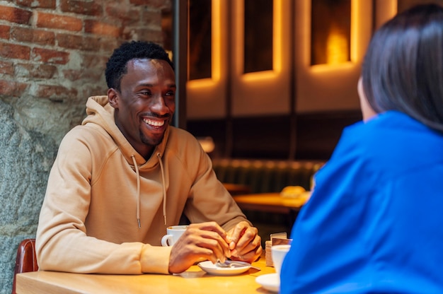 Jeune homme afro-américain souriant, buvant du café avec un ami