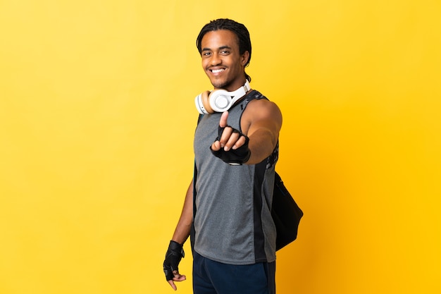 Jeune homme afro-américain de sport avec des tresses avec sac isolé sur fond jaune montrant et soulevant un doigt