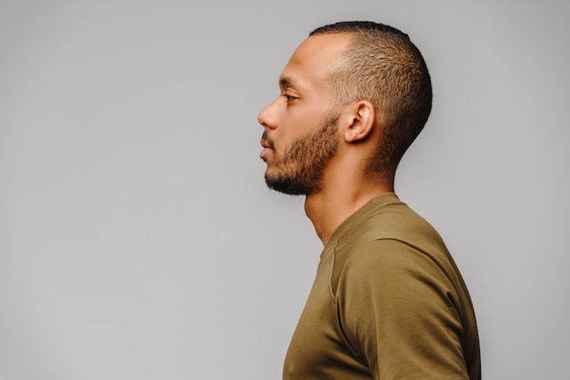 Photo jeune homme afro-américain en t-shirt vert sur mur gris clair