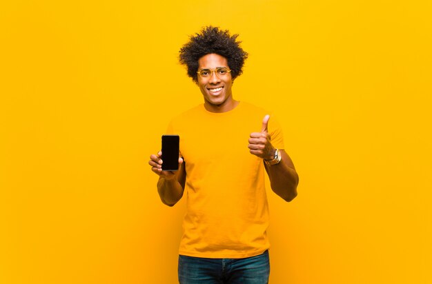 Jeune homme afro-américain avec un téléphone intelligent contre bac orange