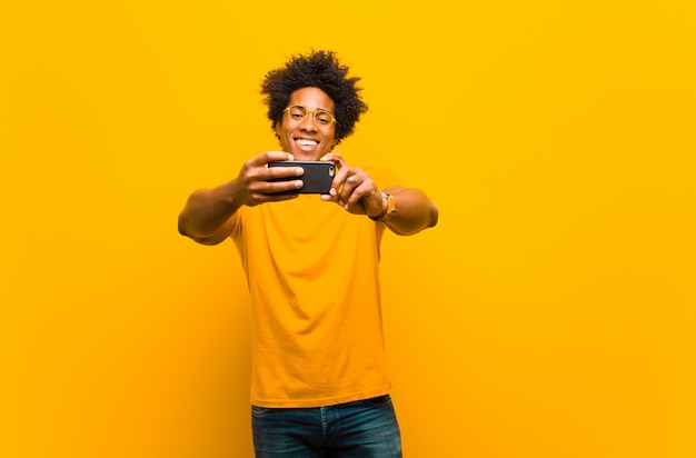 Jeune homme afro-américain avec un téléphone intelligent sur orange
