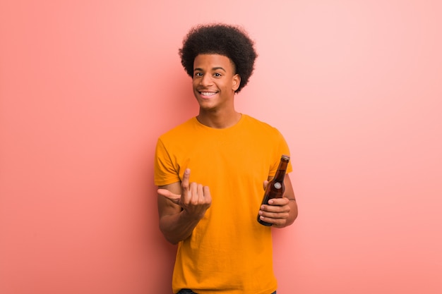 Jeune homme afro-américain tenant une bière invitant à venir