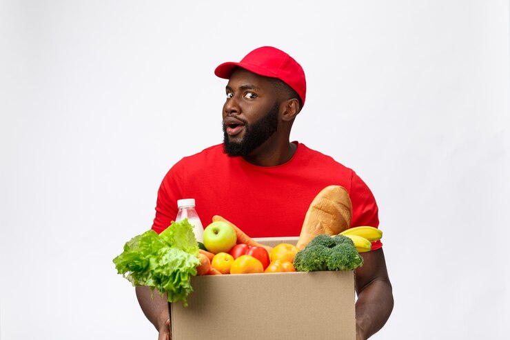 Jeune homme afro-américain tenant la boîte d'épicerie dans les mains avec un visage choquant.