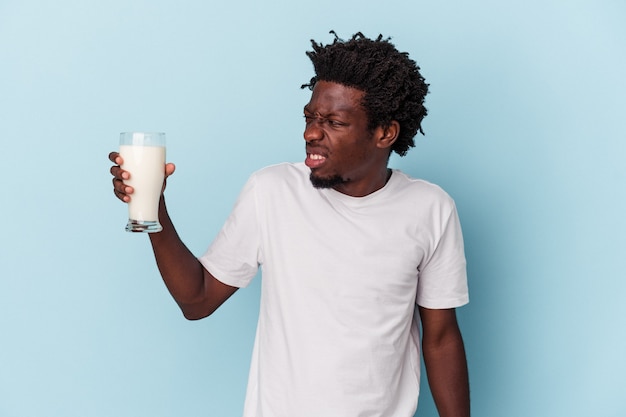 Photo jeune homme afro-américain tenant un verre de lait isolé sur fond bleu