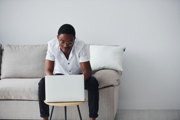 Jeune homme afro-américain en vêtements formels à l'intérieur avec un ordinateur portable dans les mains