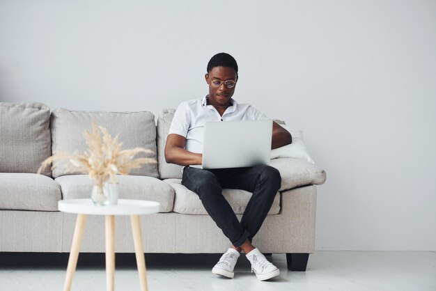 Jeune homme afro-américain en vêtements formels à l'intérieur avec un ordinateur portable dans les mains