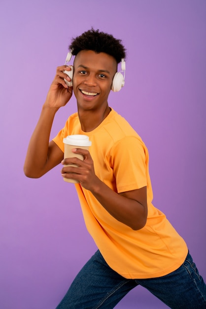 Jeune homme afro écoutant de la musique avec des écouteurs.