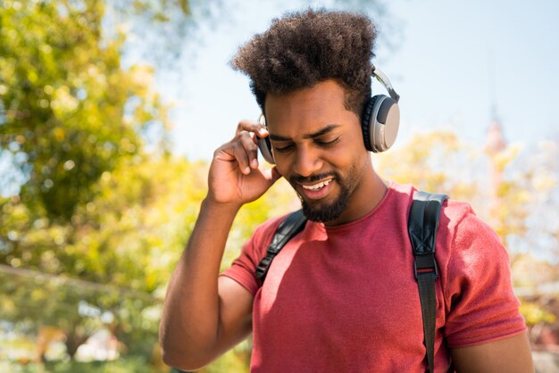 Photo jeune homme afro, écouter de la musique avec des écouteurs.