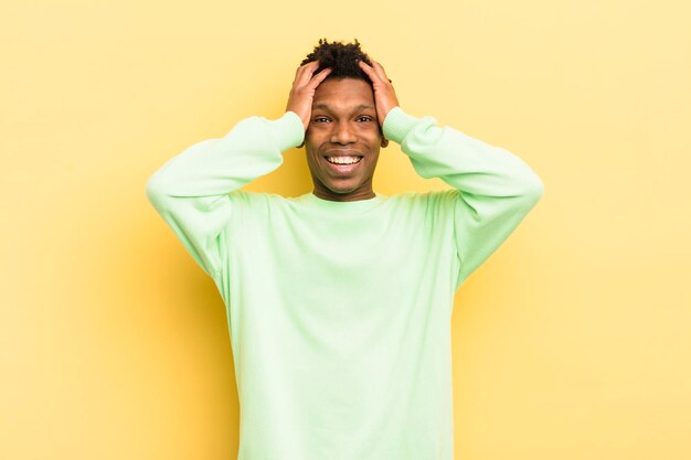 Jeune homme afro noir levant les mains à la tête bouche bée se sentant extrêmement chanceux surpris excité et heureux