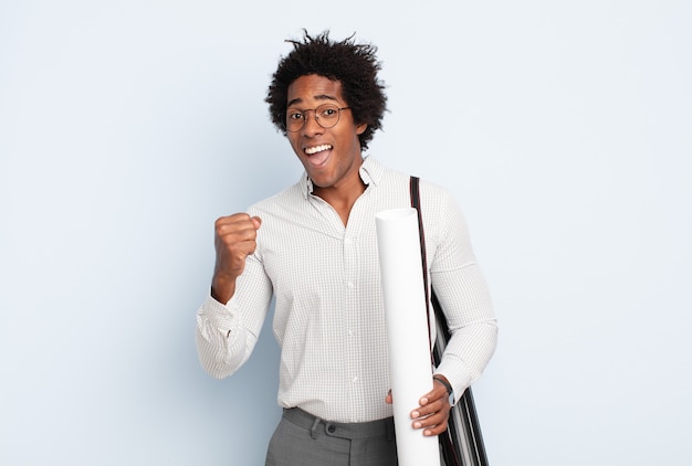 Jeune homme afro noir se sentant choqué, excité et heureux, riant et célébrant le succès, disant wow!