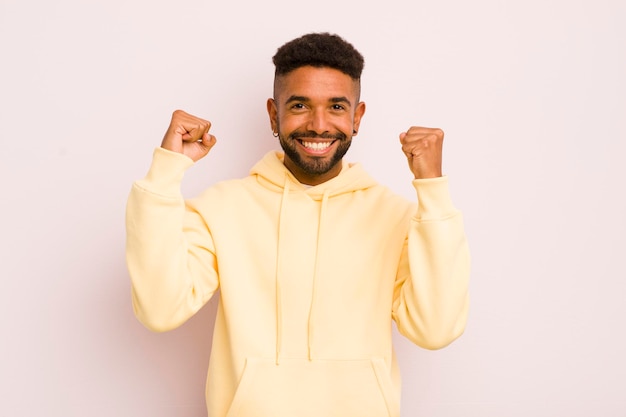 Jeune homme afro se sentant heureux surpris et fier de crier et de célébrer le succès avec un grand sourire