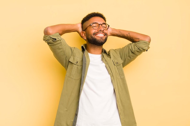 Jeune homme afro souriant et se sentant détendu, satisfait et insouciant, riant positivement et refroidissant