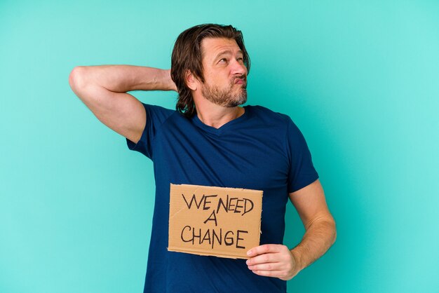 Jeune Homme D'âge Moyen De Race Blanche Tenant Un Nous Avons Besoin D'une Pancarte De Changement Isolé Sur Mur Bleu