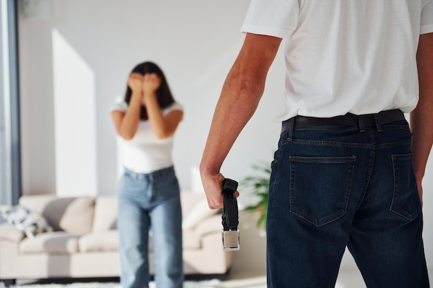 Jeune homme agressif violent avec ceinture menaçant sa petite amie à la maison