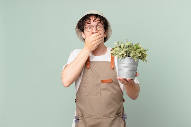 Jeune homme d'agriculteur couvrant la bouche avec des mains avec un choqué