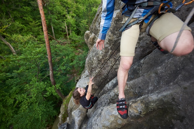 Jeune homme aidant la jeune fille escaladant le sommet des montagnes Rocheuses.