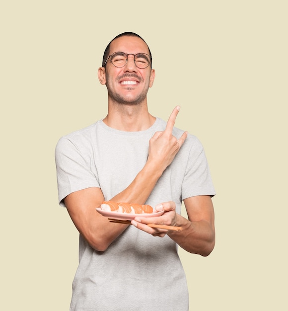 Jeune homme à l'aide de baguettes pour manger des sushis