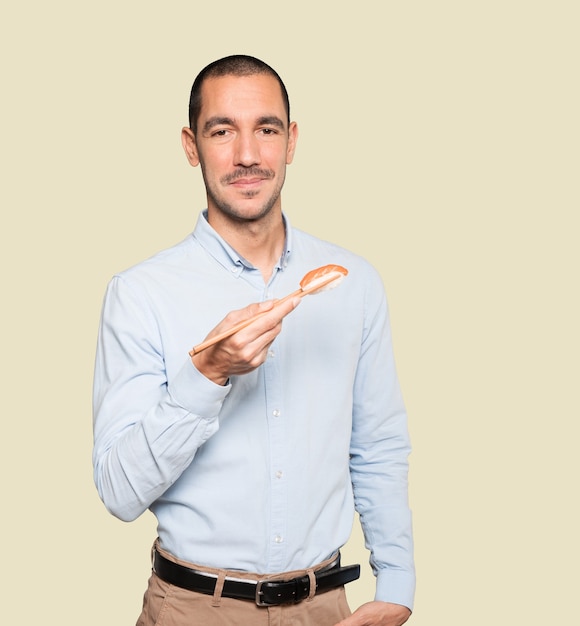 Jeune homme à l'aide de baguettes pour manger des sushis