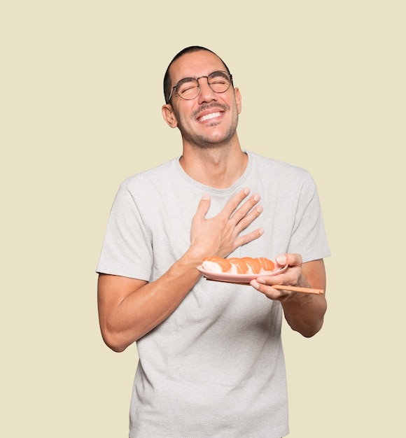 Jeune homme à l'aide de baguettes pour manger des sushis